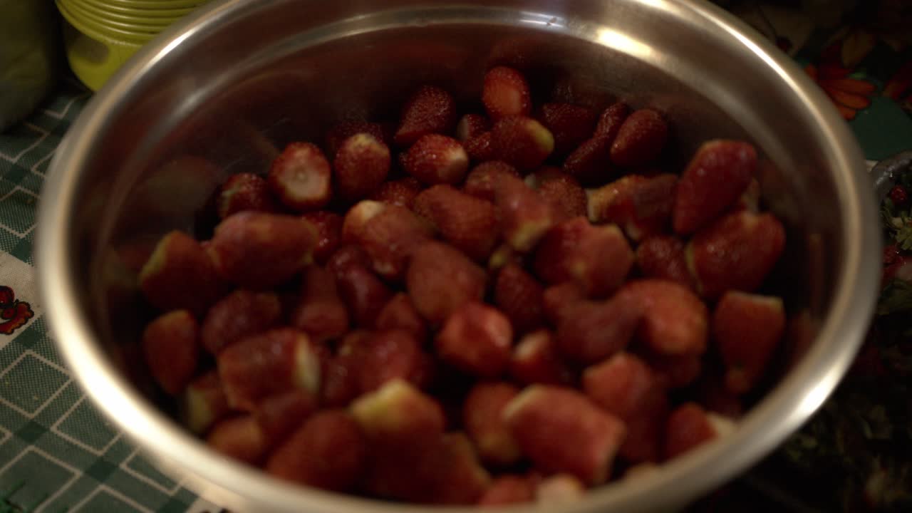 un cuenco de acero lleno de fresas maduras recién recogidas con tallos cortados, listas para el consumo