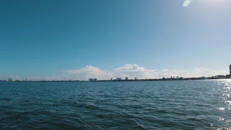 view from a boat on the bay as it approaches the city on a bright sunny day and the sun reflects off the ocean