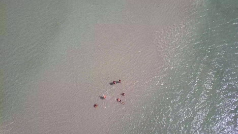 Rotierende-Drohnenansicht-Einer-Gruppe-Von-Menschen,-Die-Sich-Am-Ruhigen-Blauen-Meer-Entspannen