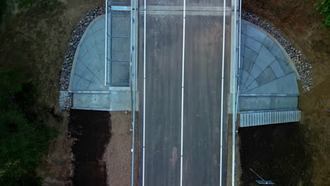 Isolated-close-up-of-a-newly-constructed-bridge-over-a-river---straight-down-aerial-view