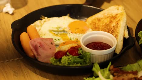 breakfast platter with eggs, toast, sausages, ham, tomatoes, and salad