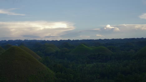 Lush-green-Chocolate-Hills-of-the-Philippines-under-a-dynamic-sky-at-dusk,-wide-shot