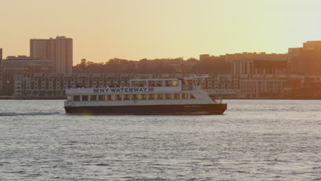 new york waterway ferry crossing the hudson past golden orange sunset light in background. tracking shot