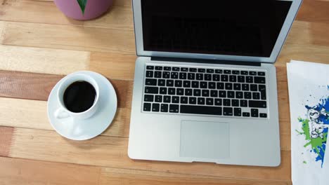 Laptop-and-cup-of-coffee-arranged-on-wooden-table