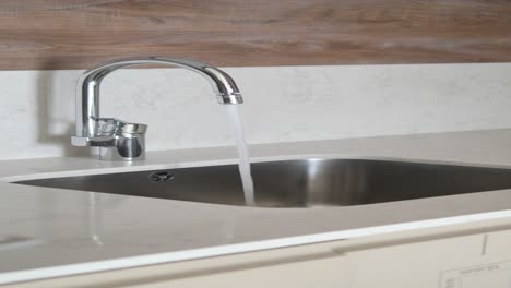 un fregadero de cocina moderno con un grifo de cromo y agua corriente