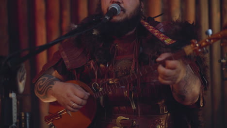 asian musician plays banjo and sings ancient song in room