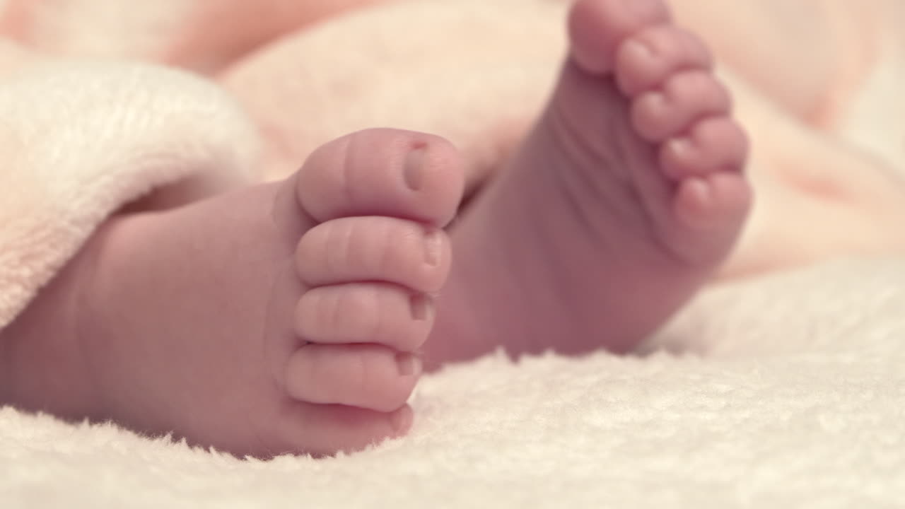 el hermoso bebé recién nacido está acostado en la cama y muestra las manos y los pies, la madre juega con el bebé y la cubre con una colcha acogedora, 4k 60p apple prores422, con grabadora de átomos externos-1