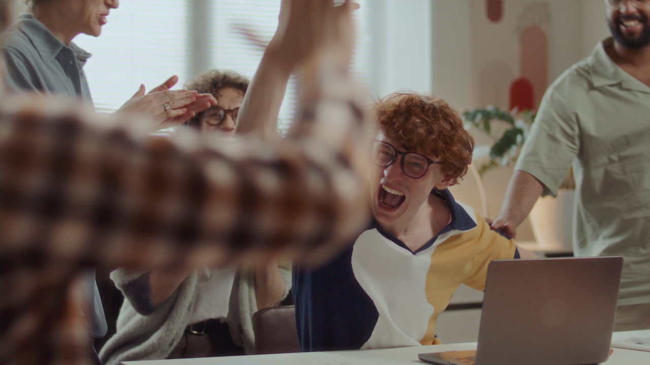 Excited Man Celebrating Successful Project with Diverse Team at Office