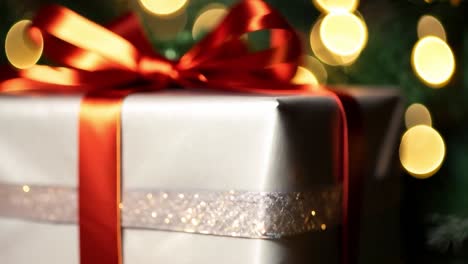 closeup of a christmas gift wrapped in white paper with a red ribbon