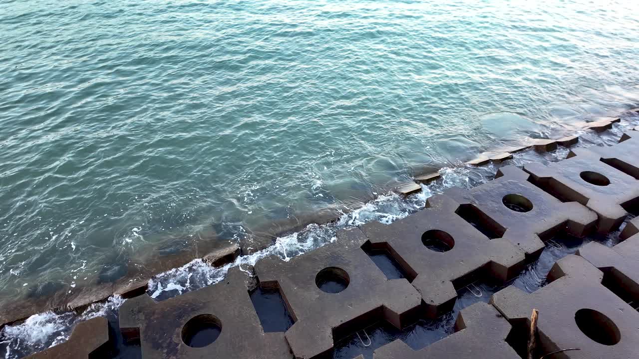 Sea waves crashing against a breakwater made of concrete blocks, protecting the coast from erosion