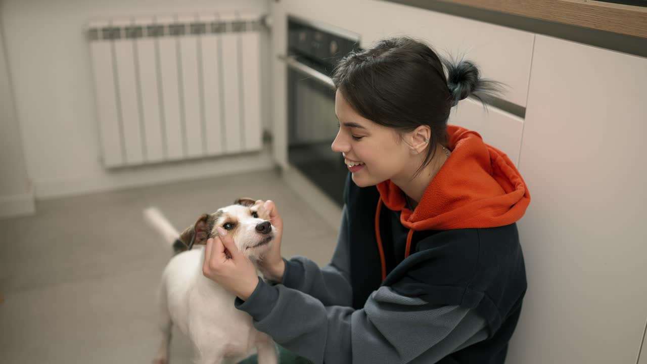 A young girl hugs her small dog in the kitchen, care and love for a pet