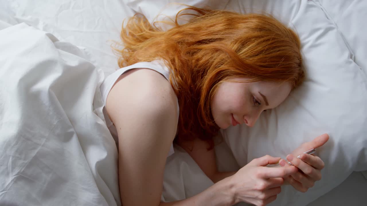 mujer usando teléfono móvil en el dormitorio 4k