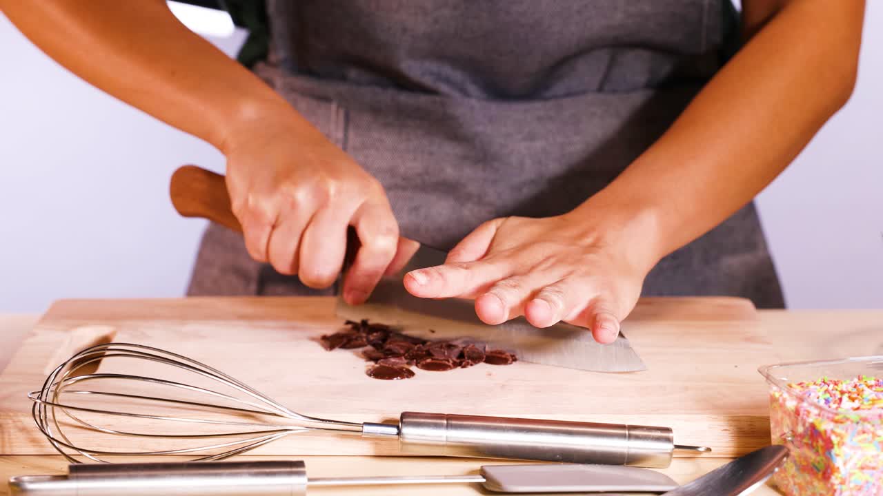 Persona che taglia dischi di cioccolato con un coltello