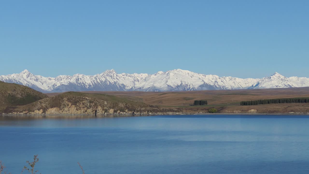 zoom estático de la hora dorada, a mediados de invierno, a través del hermoso lago alpino de color azul tinta hacia majestuosas montañas