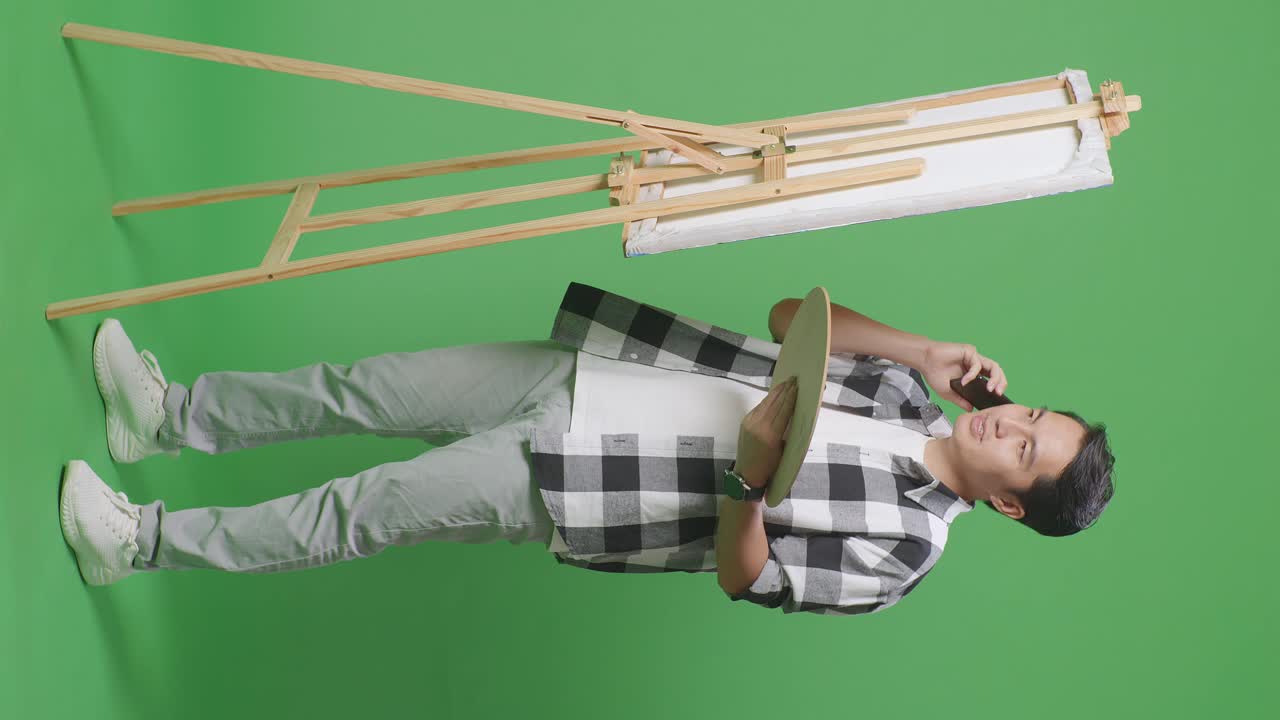 예술가 가 기둥 앞 에서 전화 로 이야기 하고 있다