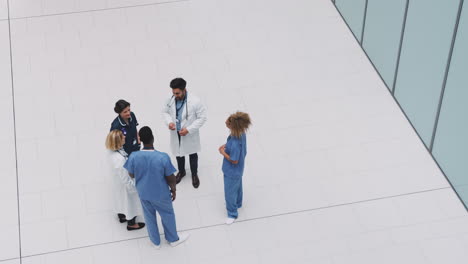 overhead view of medical staff having informal meeting in lobby of modern hospital building