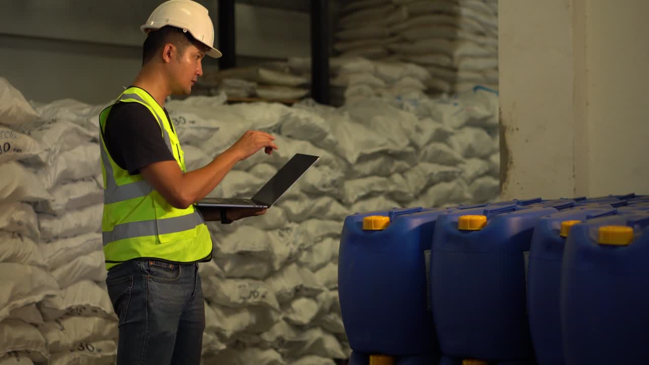 A Young manager using laptop counting chemical barrels.