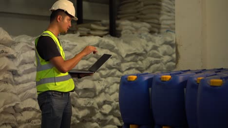 a young manager using laptop counting chemical barrels.