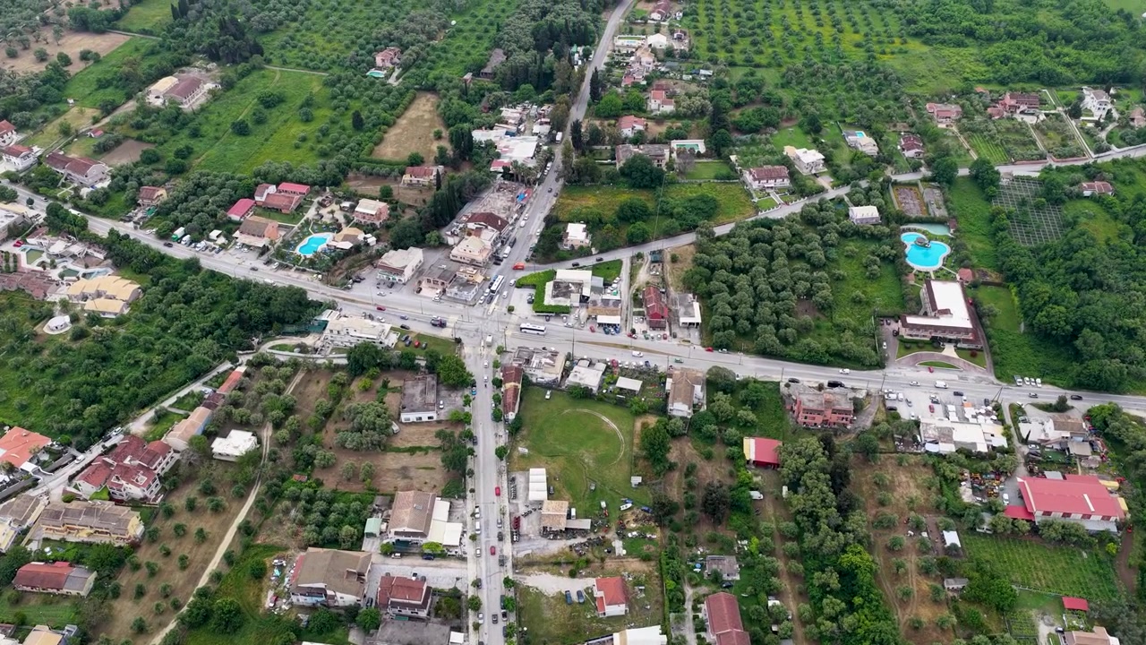 Ripresa aerea con drone della località turistica di Roda a Corfù Nord, con un incrocio stradale principale, ville e campagna.
