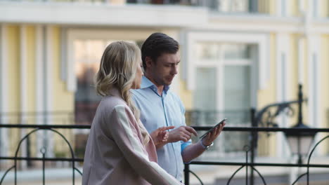 Serious-business-couple-using-tablet-computer.-Business-partners-talking-outdoor