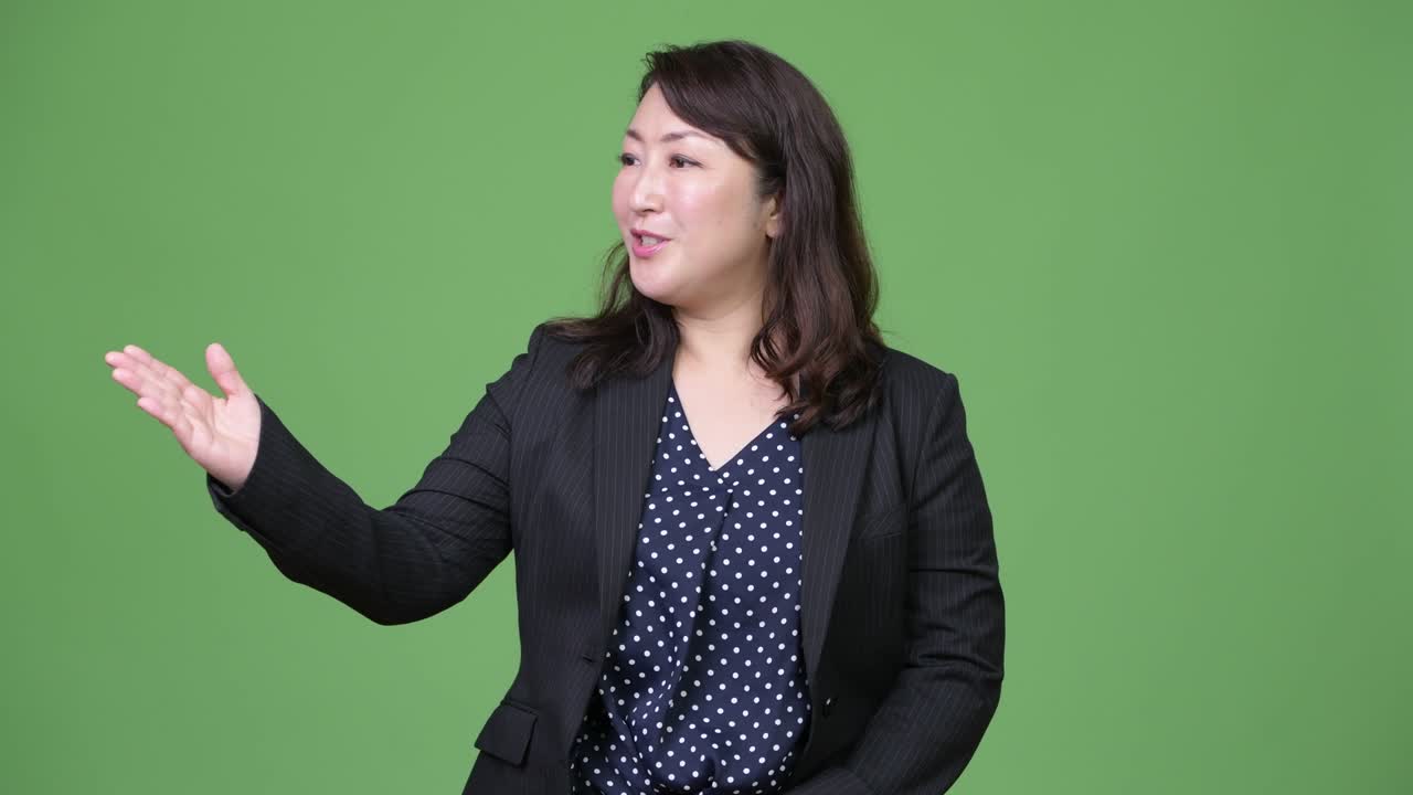 Mature beautiful Asian businesswoman talking and gesturing