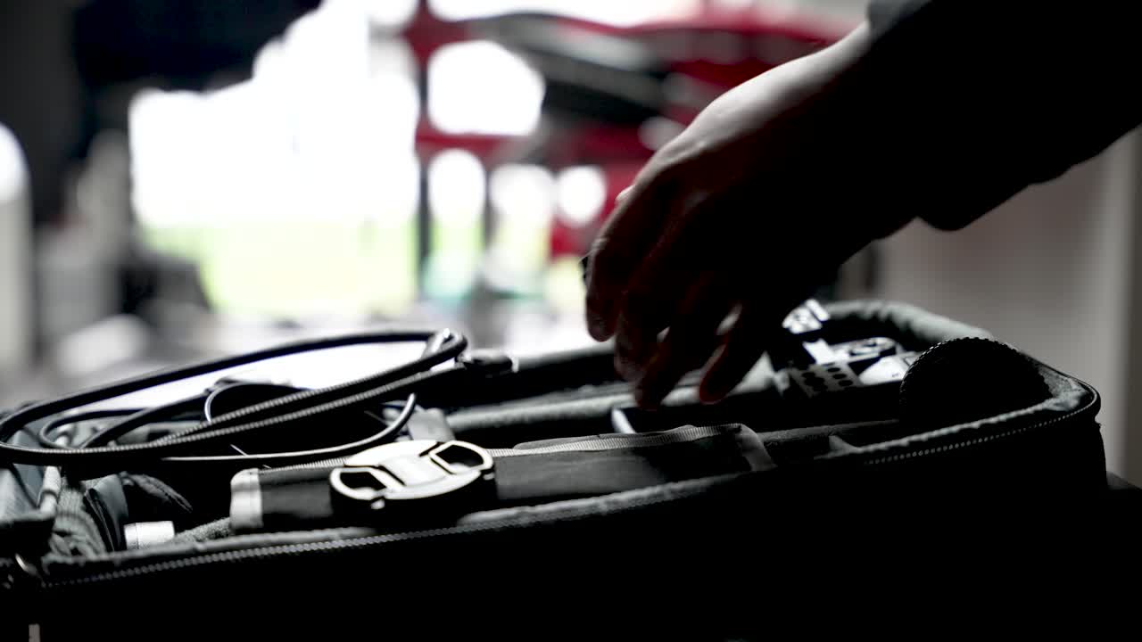 Person's hands organizing equipment inside a camera bag, preparing for a trip