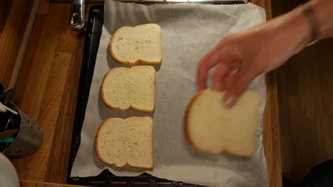 Placing-bread-pieces-on-baking-paper-for-homemade-sandiwch-preparation