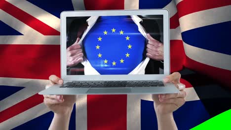 Mann-Zeigt-Europa-Shirt-Auf-Einem-Laptop,-Der-Von-Händen-Mit-Der-Flagge-Des-Vereinigten-Königreichs-Gehalten-Wird