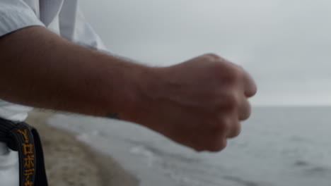 hombre de puño entrenando karate golpea en la playa de cerca. atleta haciendo ejercicios.