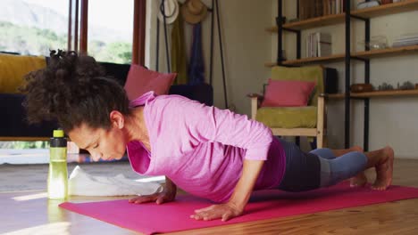 Mixed-race-woman-practicing-yoga-on-yoga-mat-at-home