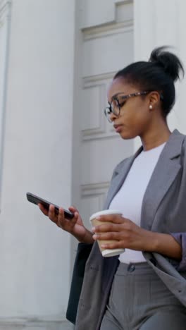 businesswoman walking outdoors with coffee and phone