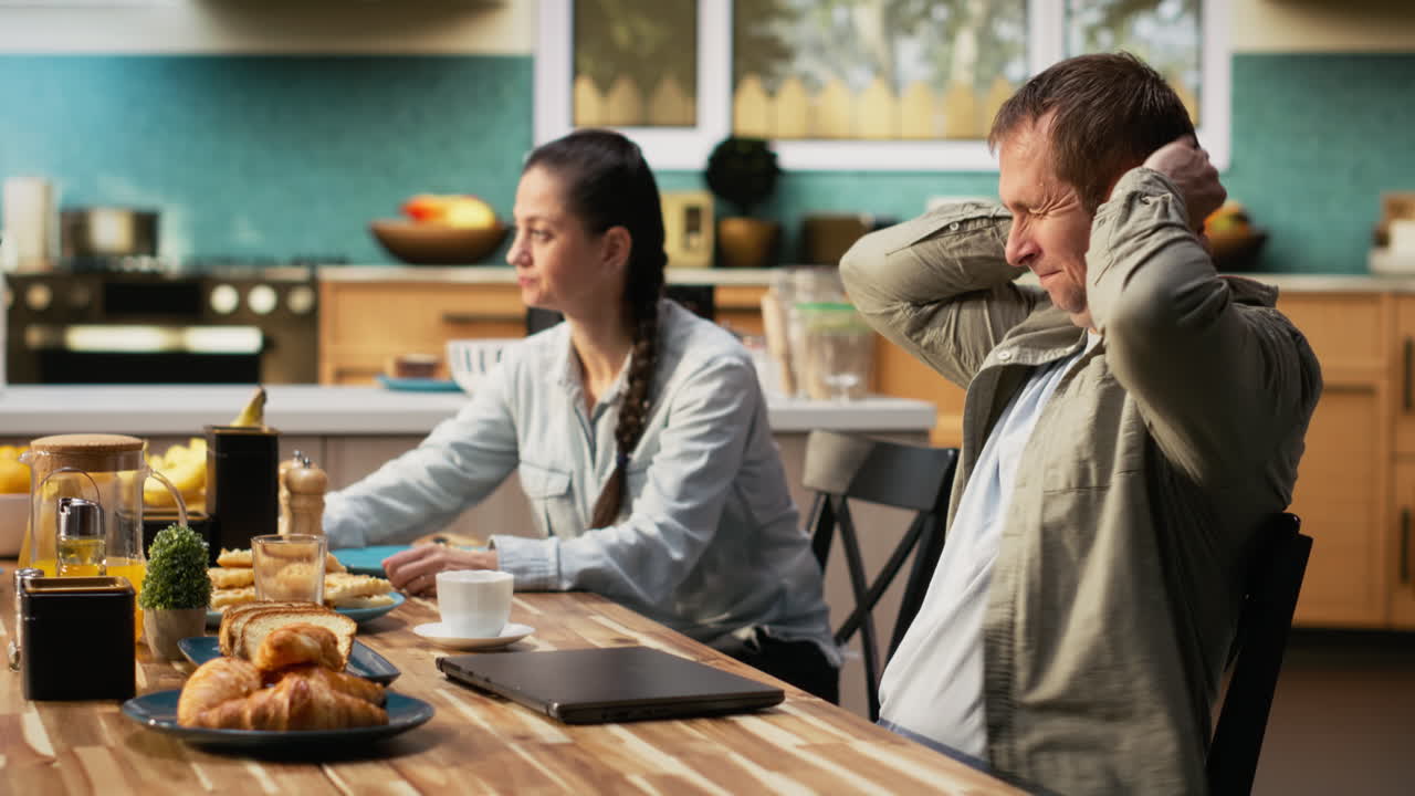 Drained weary working dad typing on laptop during breakfast