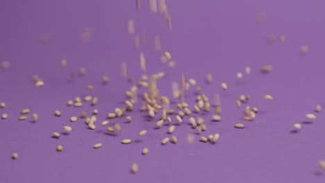 Sesame-seeds-falling-on-violet-background