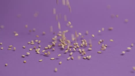 semillas de sésamo cayendo sobre un fondo violeta