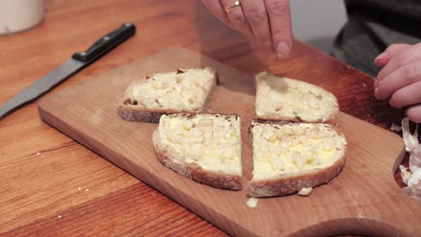 Woman's hands with salt cut two slices of bread smeared with butter and garlic