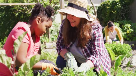 happy caucasian lesbian couple and their african american daughter gardening together