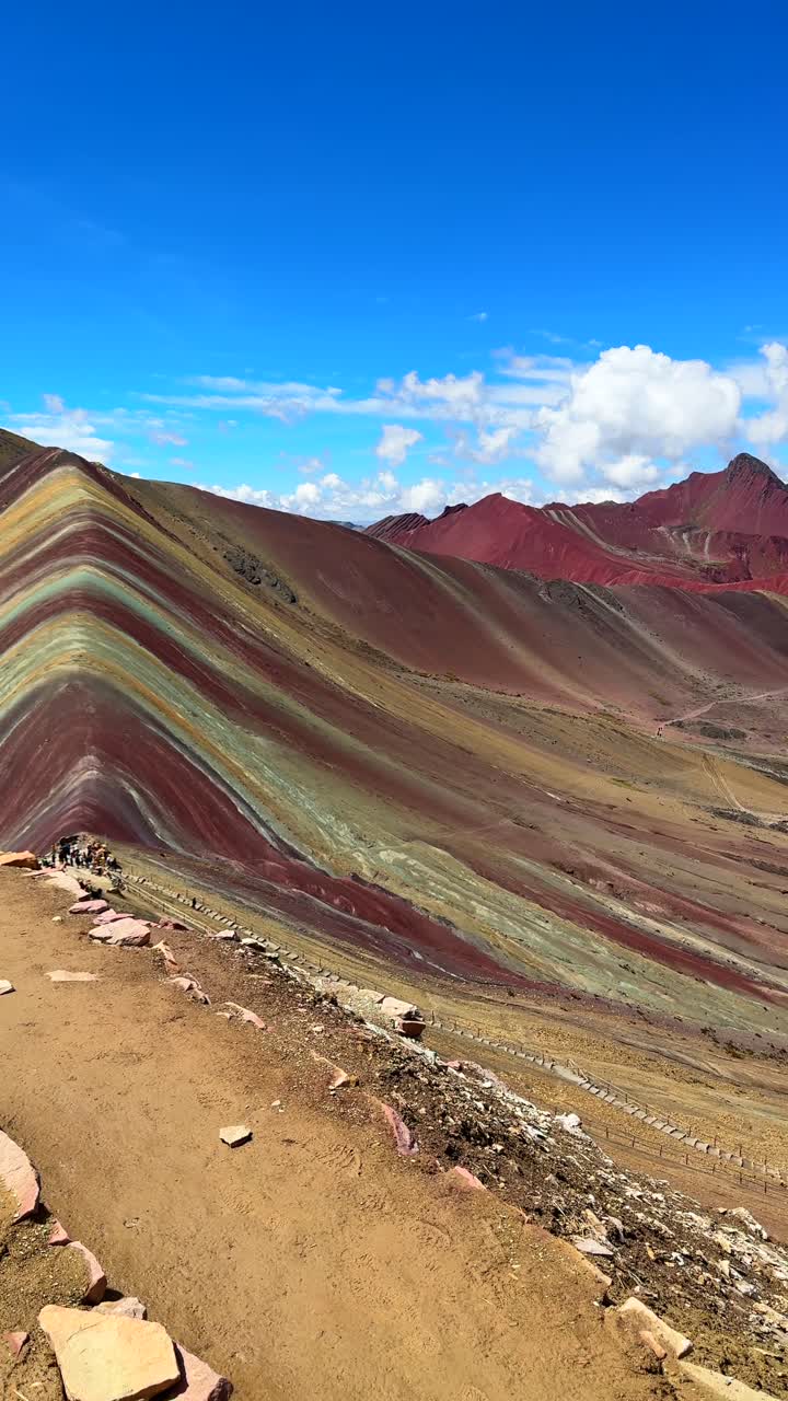 Rainbow Mountain Vinicunca vertical reel Peru Perú trail morning blue sky Montaña de Siete Colores Palccoyo Peruvian Andes Red Valley striped hills seven colored Cusco Region nature landscape pan view