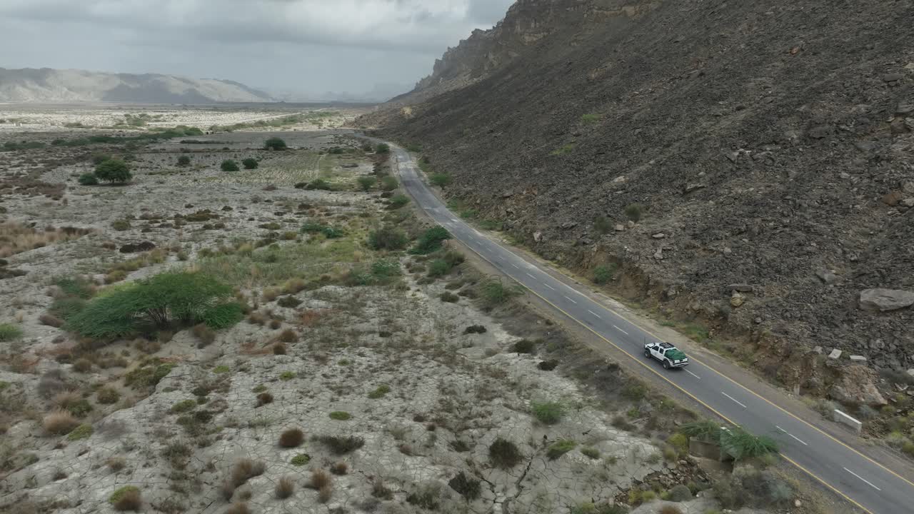 avión no tripulado siguiendo un coche en la carretera entre la montaña rocosa y el valle en hingol baluchistan pakistán
