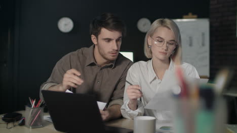 Business-couple-working-on-financial-project-in-dark-office-together.