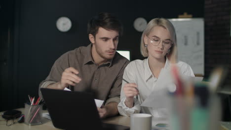 business couple working on financial project in dark office together.