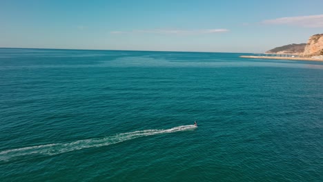 Lone-skate-surfer-riding-waves-under-blue-skies-at-Port-Ginesta,-Barcelona