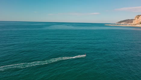 un surfista solitario montando olas bajo un cielo azul en port ginesta, barcelona