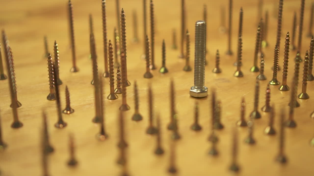 Annihilation concept, hand knocks over hundreds of upright screws, slow motion close up