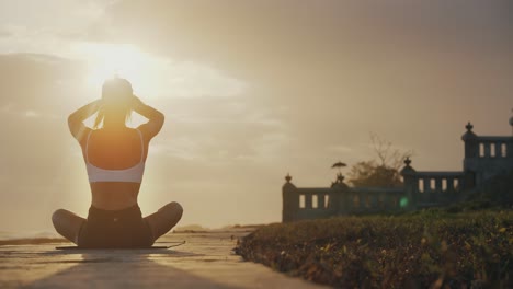 detrás de la mujer en un viaje espiritual saludando la luz del sol brillante en la pose de loto de yoga