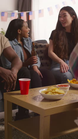 video vertical de amigos en casa riendo hablando y comiendo bocadillos celebrando en una fiesta haciendo aclamaciones con alcohol