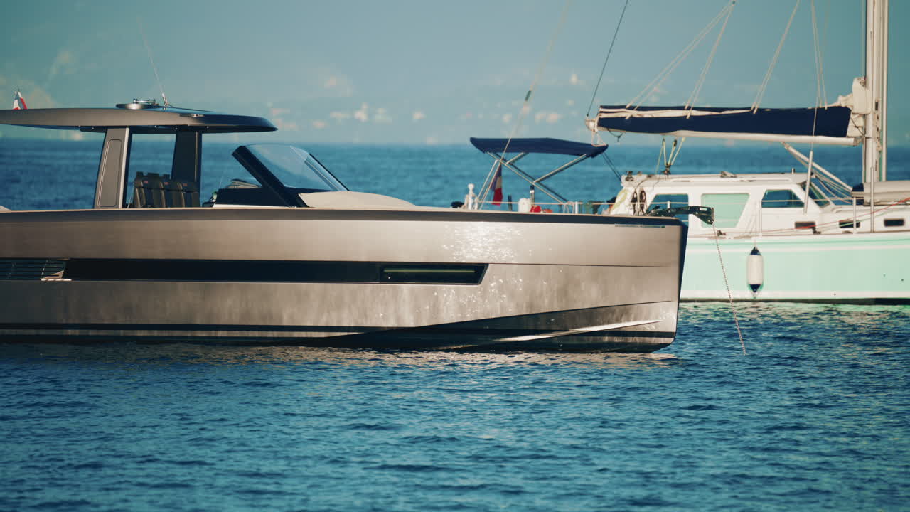 Side view of a sleek metallic yacht reflecting sunlight on calm blue water