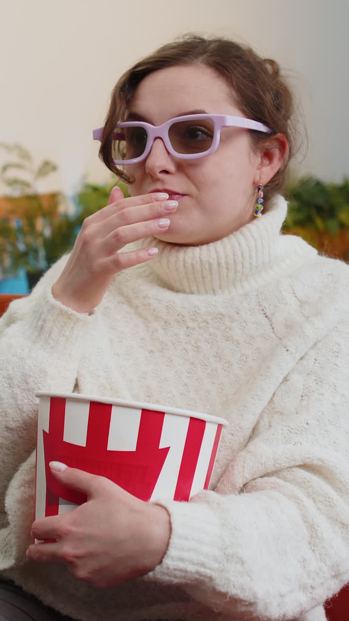 Donna seduta sul divano a mangiare popcorn e guardare interessanti TV 3D film sport gioco online a casa