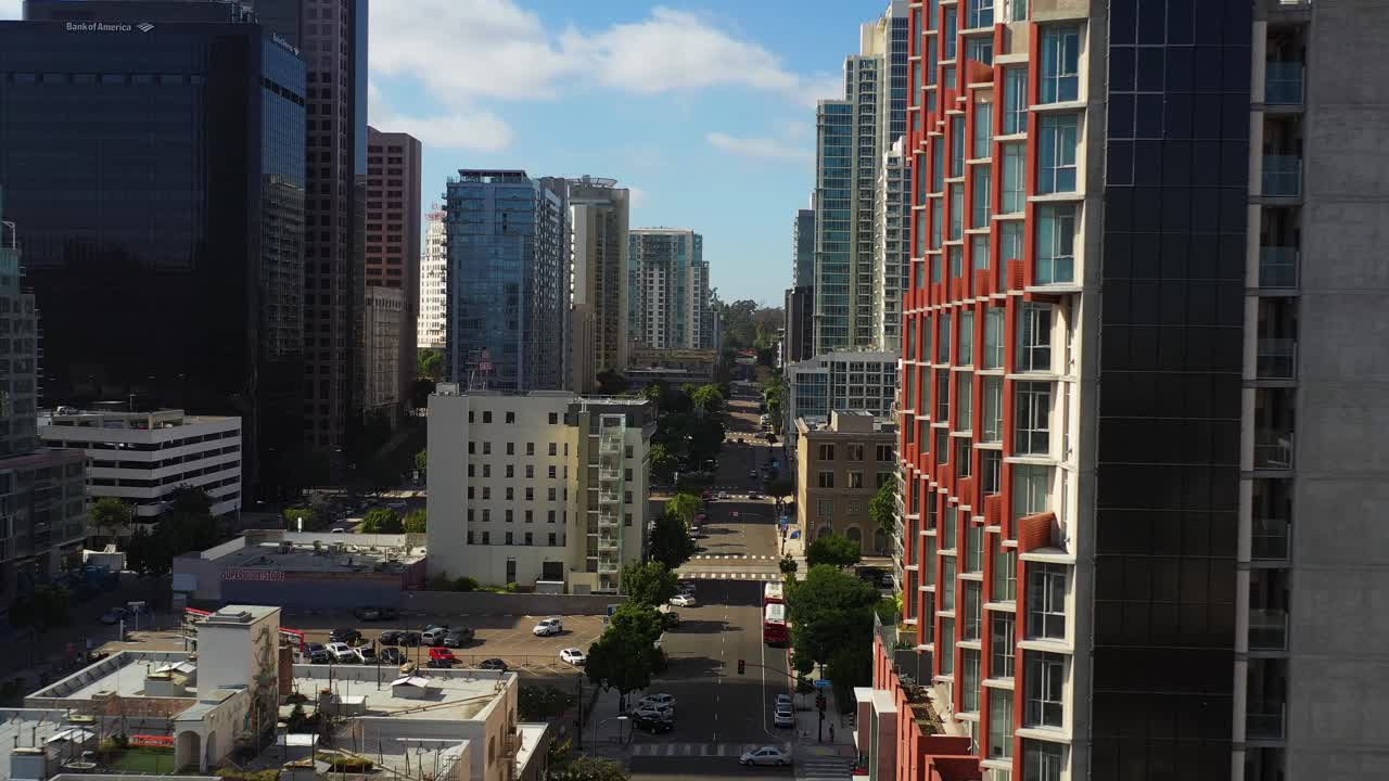 Drone recuando ao longo da 9th Street entre edifícios no centro de San Diego mostrando arquitetura urbana e ruas da cidade