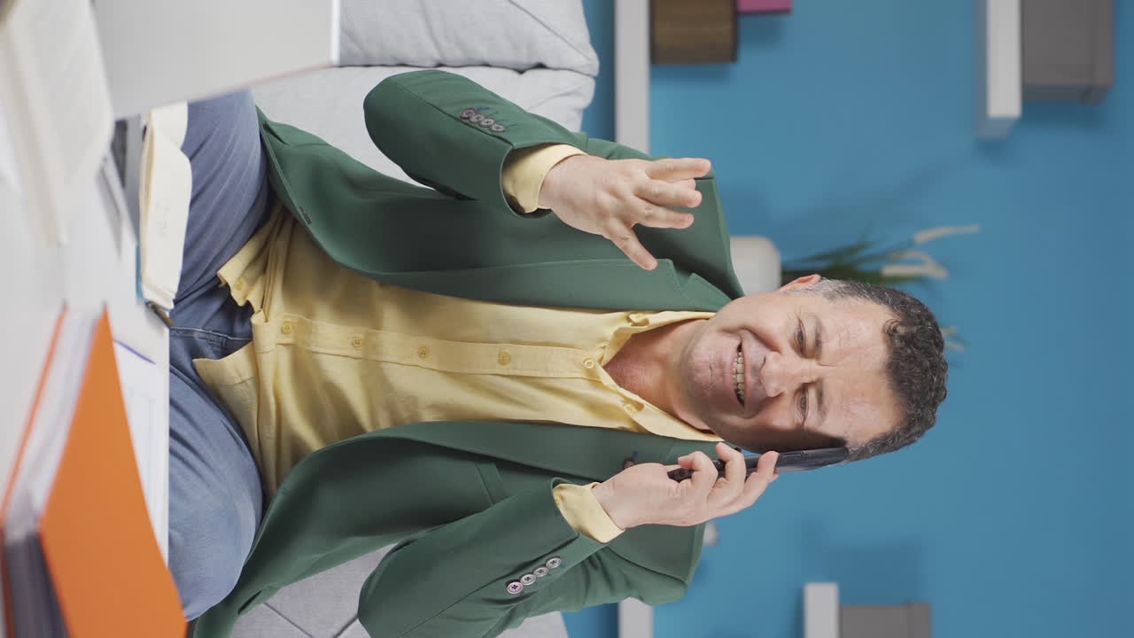 video vertical de un trabajador de oficina en casa, un anciano, un teléfono enojado, realiza una llamada de negocios.