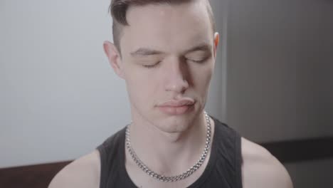 portrait of young man closing eyes while meditating alone at home